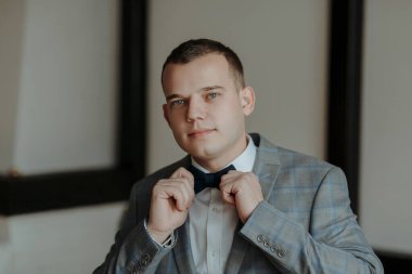 Takım elbiseli ve kravatlı bir adam papyonunu bağlamaya hazırlanıyor. Adam takım elbise ve kravat giydiği için resmiyet ve zarafet kavramı.