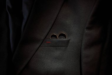 Bir adam siyah bir takım elbise giyiyor ve cebinde iki yüzük var. Zarafet ve entelektüellik anlayışı, çünkü adam resmi giyinmiş.