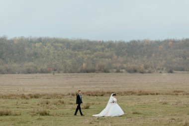 Bulutlu bir günde bir gelin ve damat tarlada yürüyorlar. Gelin beyaz bir elbise giyiyor ve damat bir takım elbise giyiyor. Sahne sakin ve huzurlu, çift birlikte yürümekten hoşlanıyor.