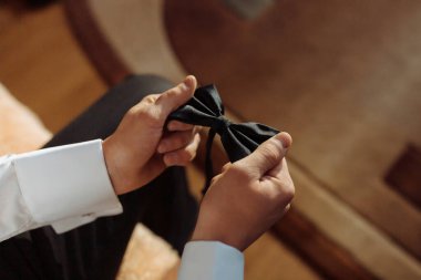 Bir adam kravatını bağlamaya hazırlanıyor. O, kravatı elinde tutuyor ve ona bakıyor.