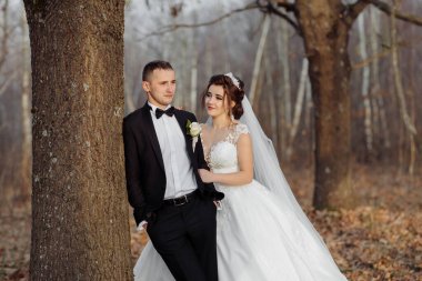Bir gelin ve damat resmi giysiler içinde bir ağacın önünde dururlar. Gelin beyaz bir elbise ve duvak giyerken damat takım elbise ve kravat takıyor. Sahne bir ormanda geçiyor.