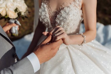 Bir erkek ve bir kadın evleniyor ve erkek kadının parmağına yüzük takıyor.