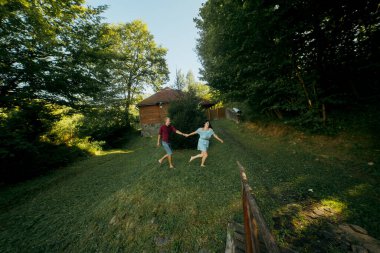 Bir çift çimenlik alanda oynuyor. Adam, kadının elini tutuyor. Sahne mutlu ve neşeli.