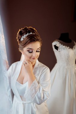 Beyaz önlüklü bir kadın, beyaz önlüklü bir şifoniyerin önünde duruyor.