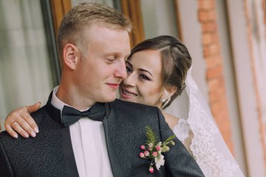 Bir erkek ve bir kadın birbirlerine sarılıyorlar, siyah takım elbiseli bir adam ve beyaz elbiseli bir kadın.