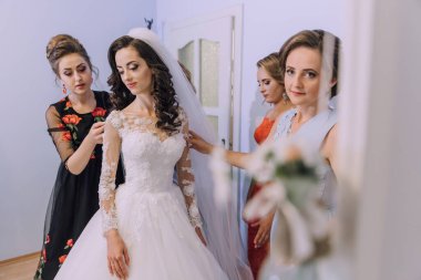 Bir gelin nedimelerinin yardımıyla düğününe hazırlanıyor. Gelin uzun beyaz bir elbise ve duvak takıyor. Nedimeler ona makyaj ve saç konusunda yardım ediyor.