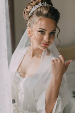 Beyaz cüppeli güzel bir gelinin portresi ve taç hazır. Kıvırcık saçlı ve moda makyajlı esmer kız..