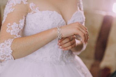 Bir kadın beyaz bir elbise ve gümüş bir bilezik takıyor. O, kameraya bakıyor. Zarafet ve entelektüellik kavramı, kadın resmi bir kıyafet giydiği için.