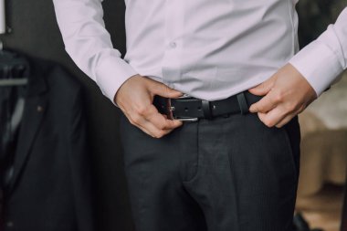 Takım elbiseli ve kravatlı bir adam kemerini ayarlıyor. Formalite ve profesyonellik kavramı. Çünkü adam takım elbise ve kravat giymiş.