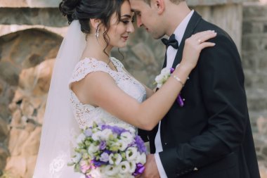 Bir gelin ve damat bir düğün töreninde birbirlerini kucaklıyorlar. Gelin beyaz bir elbise ve duvak takarken damat siyah bir takım elbise ve papyon takıyor. El ele tutuşuyorlar.