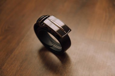 Gümüş tokalı siyah bir kuşak ahşap bir masada oturur. Kemer deriden yapılmıştır ve parlak bir görünüme sahiptir. Zarafet ve incelik kavramı