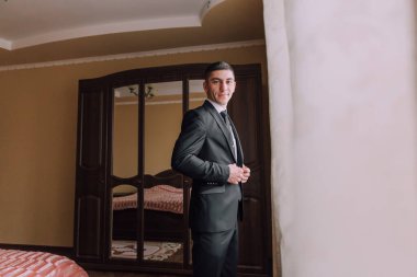 Takım elbiseli bir adam aynanın önünde kravatını düzeltiyor. Formalite ve profesyonellik kavramı. Çünkü adam takım elbise ve kravat giymiş.