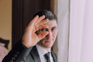 Bir adam elinde iki yüzük tutuyor, muhtemelen evleniyor. Aşk ve bağlılık kavramı, erkek yüzükleri yüzüne tutarken, muhtemelen onları birine ya da kendine göstermek için.