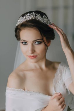 Taçlı ve beyaz elbiseli bir kadın. Gülümsüyor ve kameraya bakıyor.