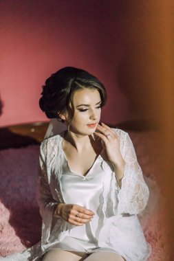 Beyaz elbiseli bir kadın yatağa oturur. O bir peçe takıyor ve elleri yüzünde.