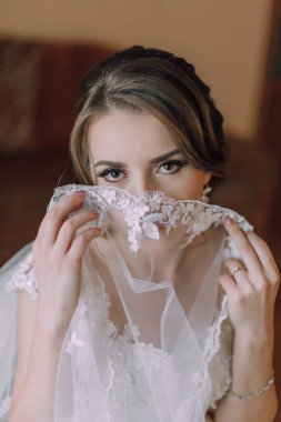 Bir kadın peçe takıyor ve kameraya bakıyor. Beyaz bir elbise giyiyor ve elleri yüzünde.