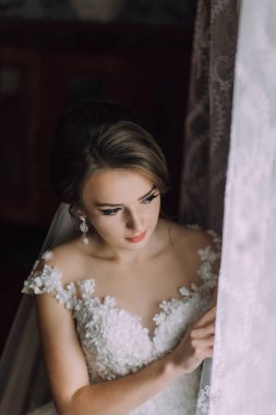 Gelinlikli bir kadın pencereden dışarı bakıyor. İmajın yumuşak ve romantik bir havası var.