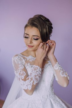 Bir kadın düğüne hazırlanıyor, gelinliğini giyiyor ve saçını düzeltiyor. Dantelli beyaz bir elbise giyiyor ve aynada kendine bakıyor.