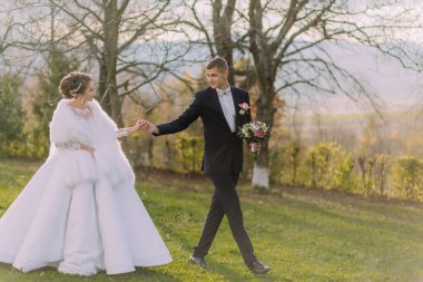 Bir gelin ve damat bir tarlada birlikte yürüyorlar. Damat siyah bir takım giyerken gelin beyaz bir elbise ve kürk şalı giyiyor. El ele tutuşup ağaca doğru yürüyorlar.