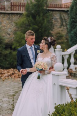 Gelin ve damat taş bir geçitte duruyorlar, gelin elinde buketle