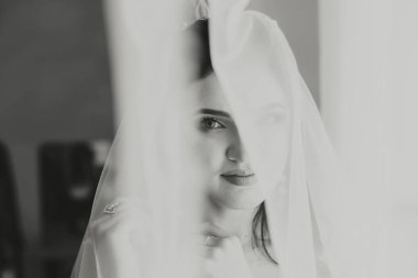 Bir kadın peçe takıyor ve kameraya bakıyor. Kadının yüzü duvak tarafından kısmen kapatıldığı için, görüntüde tuhaf ve gizemli bir his var. Siyahın kullanımı