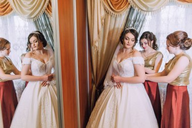 Bir gelin ve nedimeleri düğün için hazırlanıyorlar. Gelin beyaz bir elbise giyiyor ve nedimeler kırmızı elbiseler giyiyor.