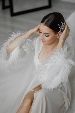 Tüylü başlıklı, beyaz elbiseli bir kadın. O, yerde oturuyor. Zarafet ve incelik kavramı