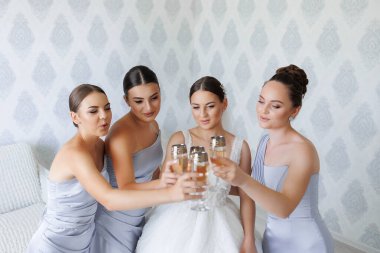 Bir grup kadın şampanyayla kadeh kaldırarak düğünü kutluyorlar. Hepsi düğün kıyafetleri içinde ve bir yatakta oturuyorlar.