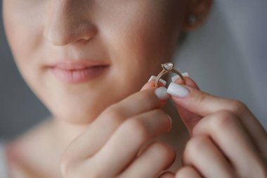 Elinde yüzük tutan bir kadın. Kadın gülümsüyor.