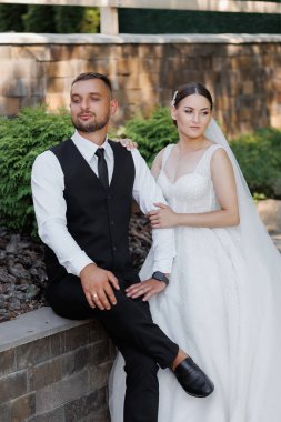 Bir adam ve bir kadın resim için poz veriyorlar. Kadın beyaz bir elbise giyerken adam siyah bir yelek ve kravat takıyor. İkisi de gülümsüyor ve mutlu görünüyorlar. Aşk ve mutluluk kavramı