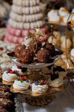 Pasta, hamur işi ve meyve içeren çeşitli tatlılar içeren bir tatlı masası. Tatlılar gümüş tepside dizilir ve üzeri böğürtlen ve diğer meyvelerle kaplanır.