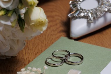 Alyans, arka planda beyaz çiçek olan yeşil bir kartta sergilenir. Yüzük aşkın ve bağlılığın sembolüdür, ve çiçek sahneye zarafet ve güzellik katar.