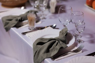 Beyaz bir masa örtüsü, iki şarap bardağı ve iki çatallı gümüş bir set.