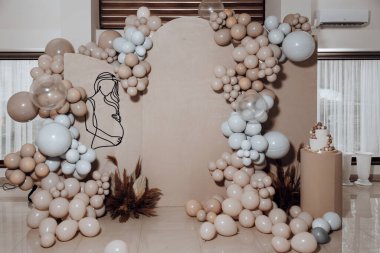 Bir kadının silueti, çok sayıda balonla çevrili bir duvara yansıtılır. Balonlar değişik boyutlarda ve renklerde, tuhaf ve eğlenceli bir atmosfer yaratıyorlar.