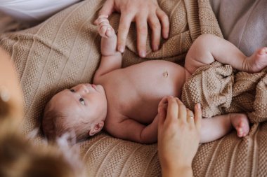 Bir bebek üzerinde insan eli olan bir battaniyenin üzerinde yatıyor. Bebek o kişiye bakıyor.