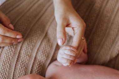 Bir bebeğin eli bir kadının eliyle tutuluyor. Bebek küçük ve kadın nazik.