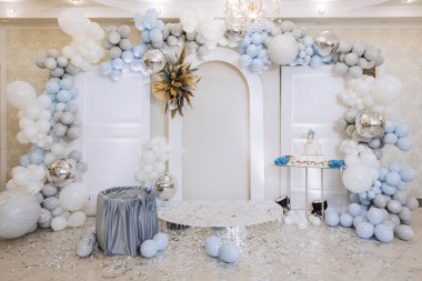 Mavi kemerli ve beyaz balonlu beyaz ve mavi bir oda. Oda bebek partisi için dekore edildi.