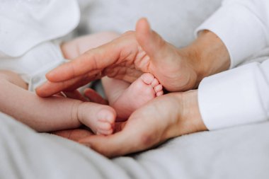 Bir bebek iki kişi tarafından tutuluyor, içlerinden biri bebeğin ayağını tutuyor. Sıcaklık ve sevgi kavramı, iki insan bebeğe rahatlık ve bakım sağlarken