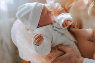 Bebeğin başında beyaz şapkası olan biri tarafından bir bebek tutuluyor. Bebek uyuyor ve insan bebeği göğsüne yakın bir yerde tutuyor. Sıcaklık ve şefkat kavramı