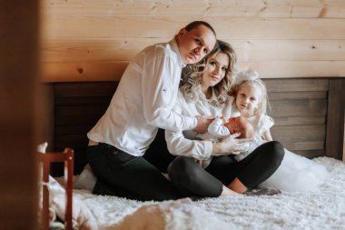 Dört kişilik bir aile, bir bebek de dahil, bir yatakta oturuyor. Adam bebeği tutuyor, ve kadın da onun yanında oturuyor. Sahne sıcak ve sevgi dolu, çünkü aile birlikte kaliteli zaman geçiriyor.