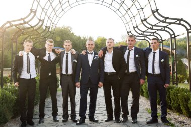 Takım elbiseli ve kravatlı bir grup adam fotoğraf için poz veriyor. Sahne resmi ve profesyoneldir.