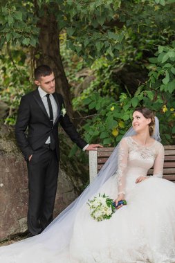 Bir adam ve bir kadın bankta oturuyor, adam takım elbise ve kravat takıyor. Gülümsüyorlar ve birbirlerinin arkadaşlığından hoşlanıyor gibi görünüyorlar. Kadın elinde bir buket çiçek tutuyor.