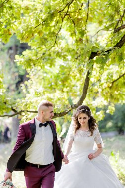 Bir adam ve bir kadın parkta birlikte yürüyorlar. Adam kırmızı bir elbise giyiyor ve kadın beyaz bir elbise giyiyor.