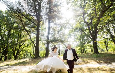 Bir gelin ve damat ağaçlarla çevrili bir ormanda yürüyorlar. Gelin beyaz bir elbise giyiyor ve damat bir takım elbise giyiyor. Sahne romantik ve huzurlu.