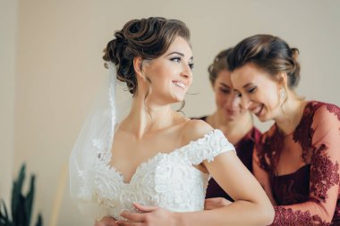 Bir gelin nedimeleriyle düğününe hazırlanıyor. Beyaz bir elbise ve duvak takıyor. Nedimeler hazırlanmasına yardım ediyor ve gülümsüyorlar. Sahne mutlu ve kutlama dolu.