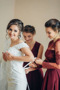 Bir gelin, nedimeleri ona yardım ederken düğününe hazırlanıyor. Gelin beyaz bir elbise giyiyor ve nedimeler kırmızı elbiseler giyiyor. Sahne neşeli ve kutlayıcıdır.