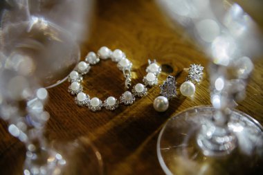 Bir bilezik ve küpeler şarap kadehinin yanındaki masada sergilenir. Zarafet ve incelik kavramı, mücevher ve şarap kadehi genellikle özel durumlarla ilişkilendirilir.