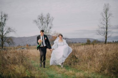 Bir gelin ve damat düğün günlerinde bir tarlada yürüyorlar. Gelin beyaz bir elbise giyiyor ve damat bir takım elbise giyiyor. Çift el ele tutuşuyor ve o da özel günlerinin tadını çıkarıyor.