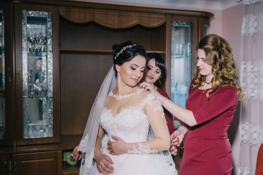 Bir gelin nedimelerinin yardımıyla düğününe hazırlanıyor. Gelin beyaz bir elbise ve duvak takarken nedimeler ona saçı ve makyajı için yardım ediyorlar.