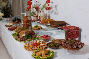 Bir masa et, sebze ve tatlılar dahil olmak üzere çeşitli yiyeceklerle kaplıdır. Masa büyük bir toplantı için hazırlandı ve yemekler görsel olarak çekici ve davetkar bir şekilde düzenlendi.